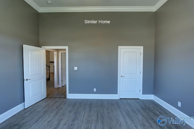 unfurnished room featuring crown molding, a high ceiling, wood finished floors, and baseboards