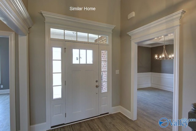 foyer with a decorative wall, dark wood-style floors, wainscoting, and a chandelier