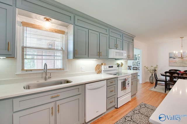 kitchen featuring a sink, white appliances, and light countertops