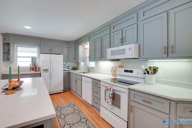 kitchen featuring white appliances, gray cabinetry, a sink, and light countertops