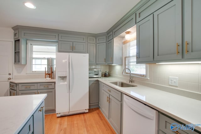kitchen with a sink, light countertops, tasteful backsplash, and white appliances