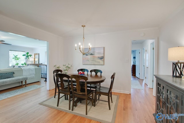dining area with ornamental molding, light wood-style flooring, and a notable chandelier