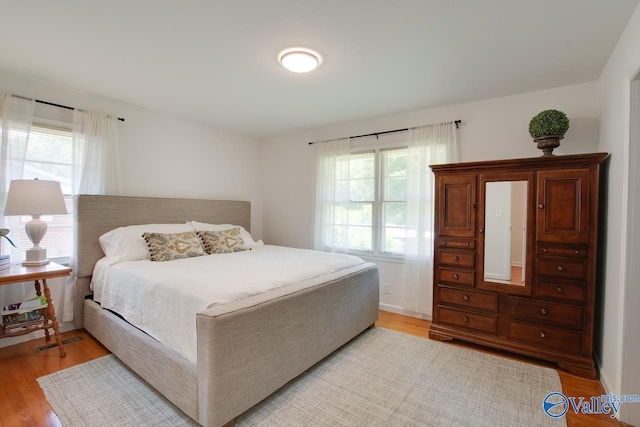 bedroom with multiple windows and light wood finished floors