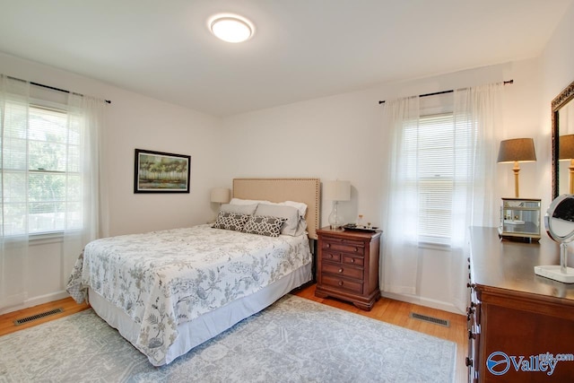 bedroom with baseboards, wood finished floors, and visible vents