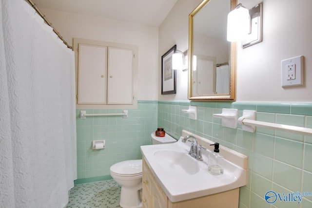 full bathroom featuring toilet, tile walls, a wainscoted wall, and vanity