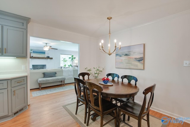 dining space featuring crown molding, light wood-style flooring, baseboards, and an inviting chandelier