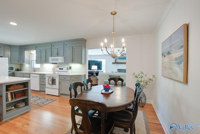 dining area featuring an inviting chandelier, ornamental molding, light wood-style flooring, and a wealth of natural light