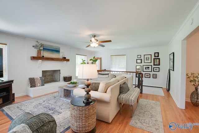 living area featuring ceiling fan, a fireplace, and light wood-type flooring