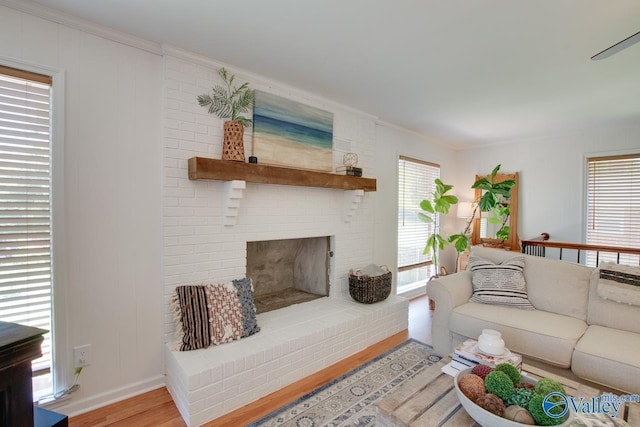 living area with baseboards, ornamental molding, light wood finished floors, and a fireplace