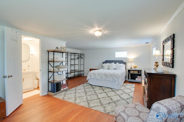 bedroom featuring connected bathroom, ornamental molding, and wood finished floors