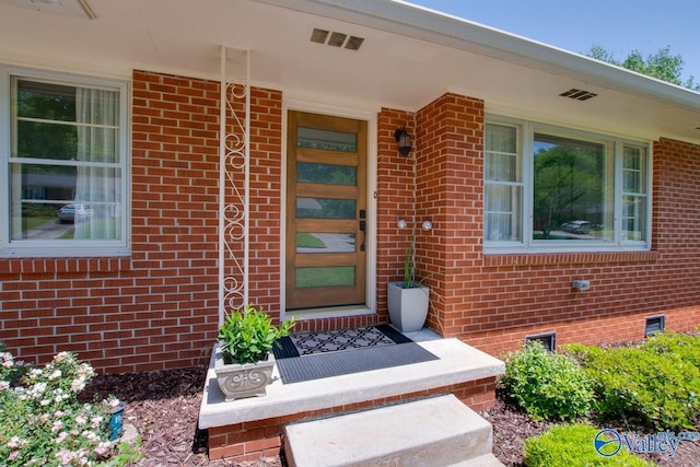 doorway to property with visible vents and brick siding