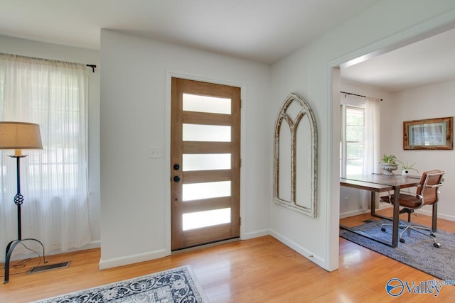 entryway with baseboards, visible vents, and light wood finished floors