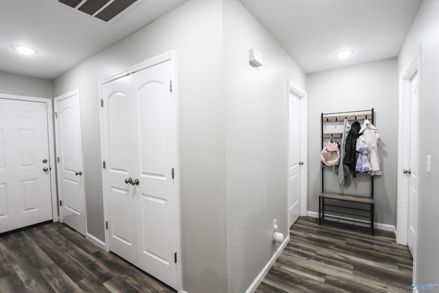 hallway featuring visible vents, baseboards, and dark wood-style flooring