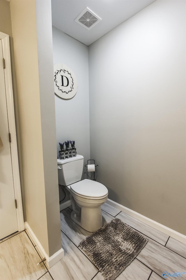 bathroom featuring visible vents, baseboards, toilet, and wood finished floors