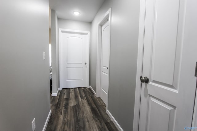 hall featuring dark wood-type flooring and baseboards