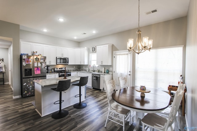 kitchen featuring visible vents, a kitchen island, a chandelier, appliances with stainless steel finishes, and white cabinets