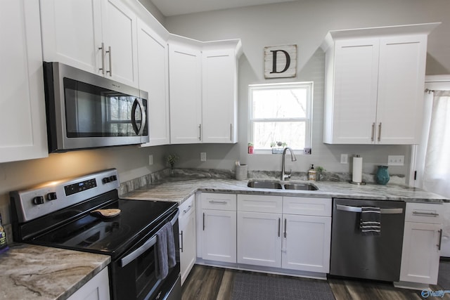 kitchen featuring white cabinets, light stone counters, appliances with stainless steel finishes, and a sink