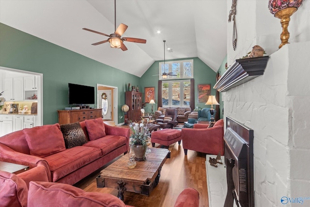 living room with hardwood / wood-style flooring, ceiling fan, a fireplace, and lofted ceiling