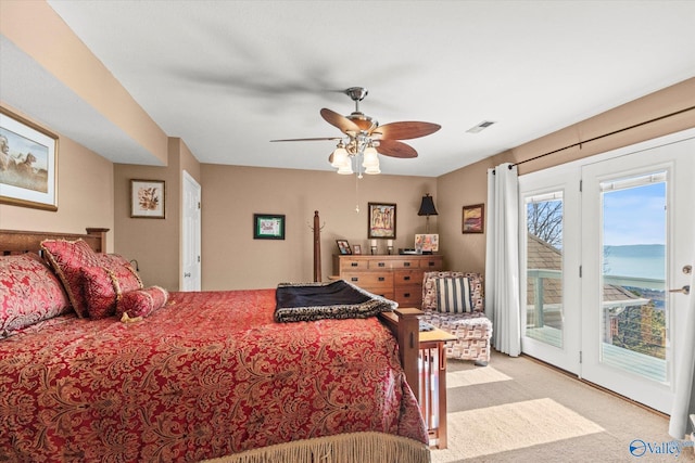 bedroom with ceiling fan, light carpet, access to outside, and a water view