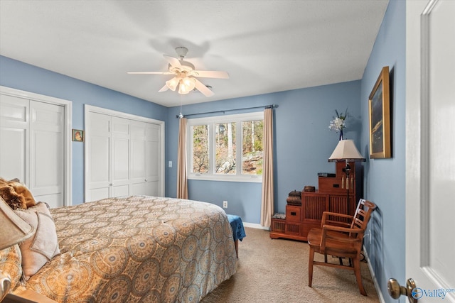 carpeted bedroom featuring ceiling fan and two closets