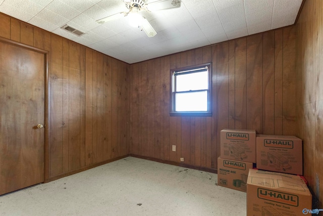 unfurnished room featuring wooden walls and ceiling fan