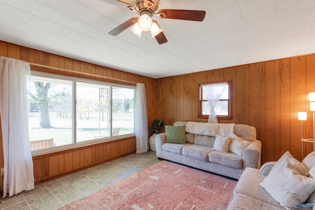 living room with a healthy amount of sunlight, wooden walls, and ceiling fan