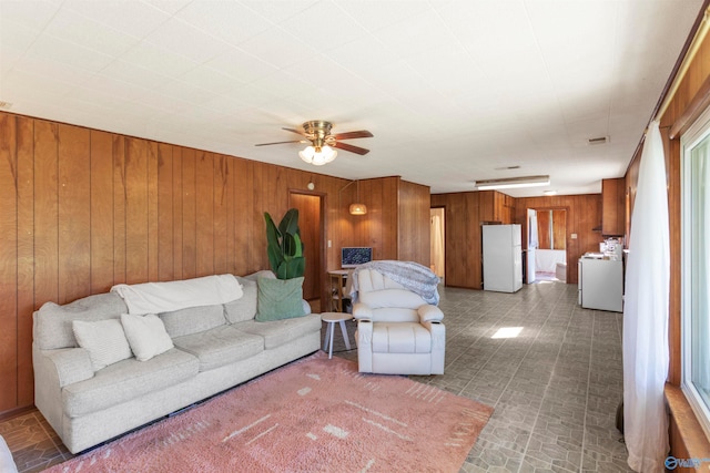 living room with ceiling fan and wood walls