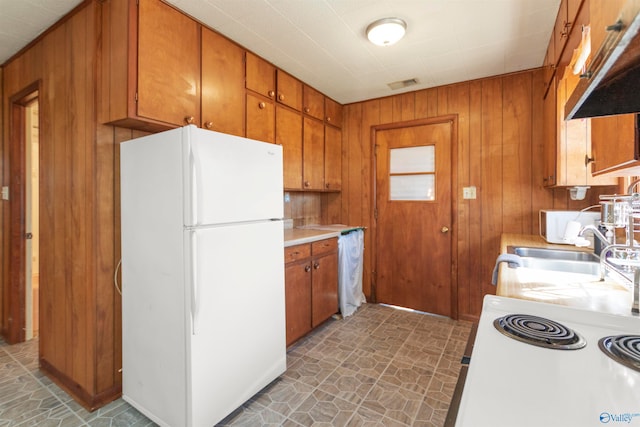 kitchen with wood walls, sink, and white refrigerator