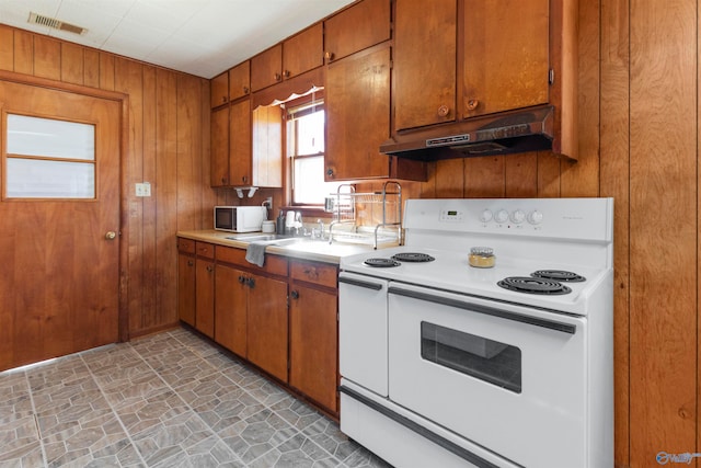 kitchen with sink, wooden walls, and white appliances