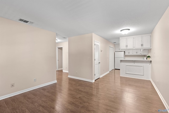 unfurnished living room featuring visible vents, baseboards, and wood finished floors