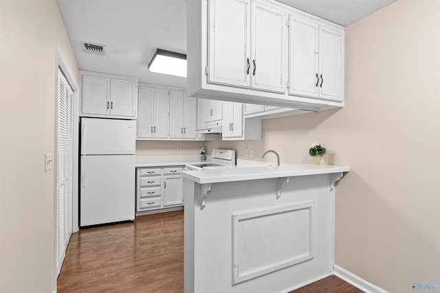 kitchen with white cabinetry, light countertops, white appliances, and visible vents