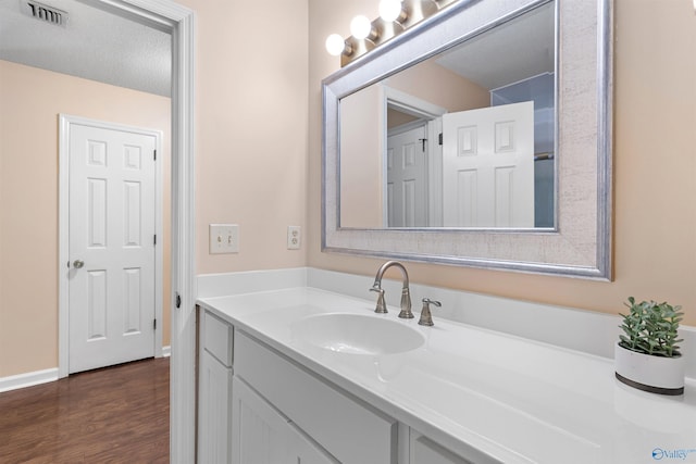 bathroom with visible vents, vanity, and wood finished floors