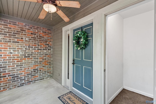 doorway to property featuring ceiling fan and brick siding