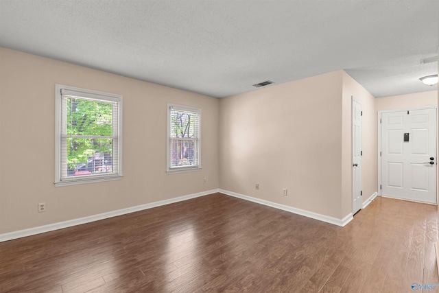empty room with wood finished floors, baseboards, and visible vents