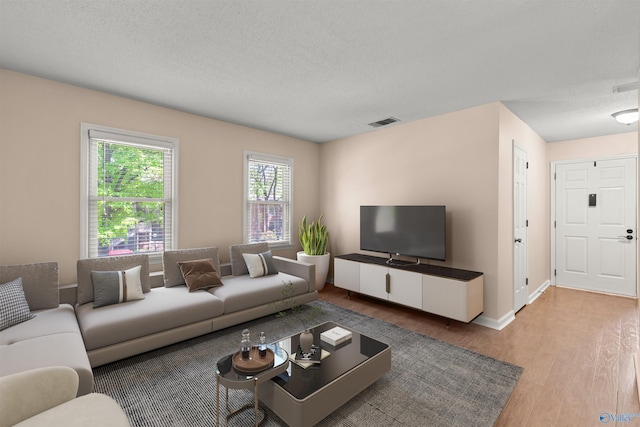 living room featuring visible vents, baseboards, wood finished floors, and a textured ceiling