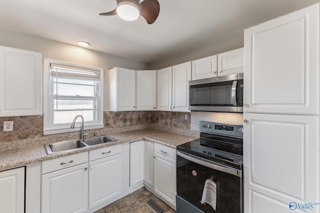 kitchen featuring visible vents, backsplash, appliances with stainless steel finishes, white cabinets, and a sink