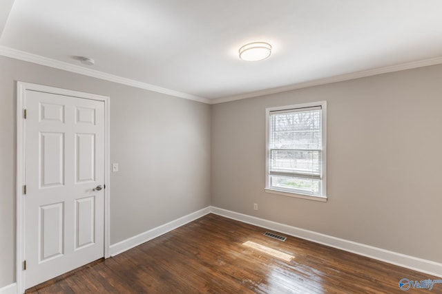 spare room with visible vents, dark wood-type flooring, baseboards, and ornamental molding