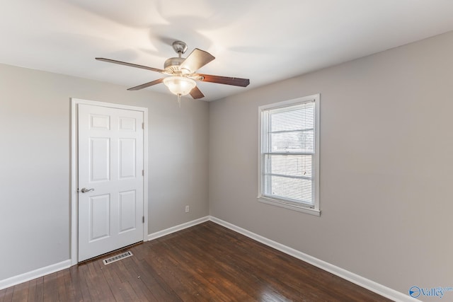 empty room with ceiling fan, visible vents, baseboards, and dark wood-style floors