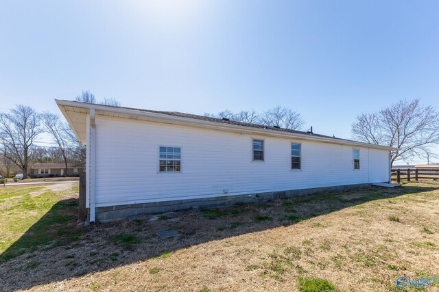 view of property exterior with a lawn and fence