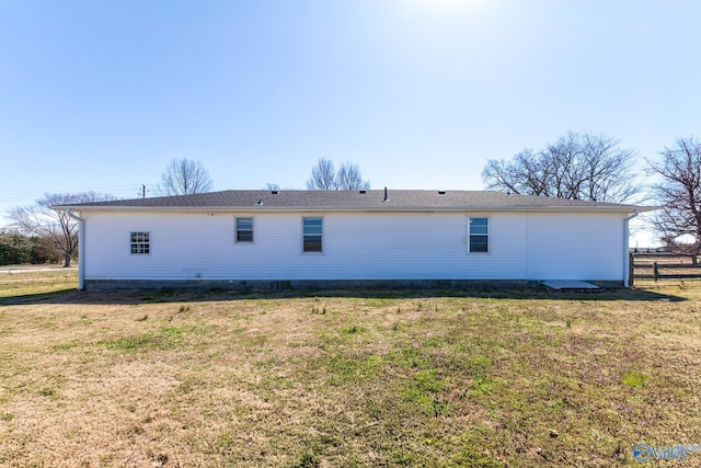 rear view of house featuring a lawn and fence