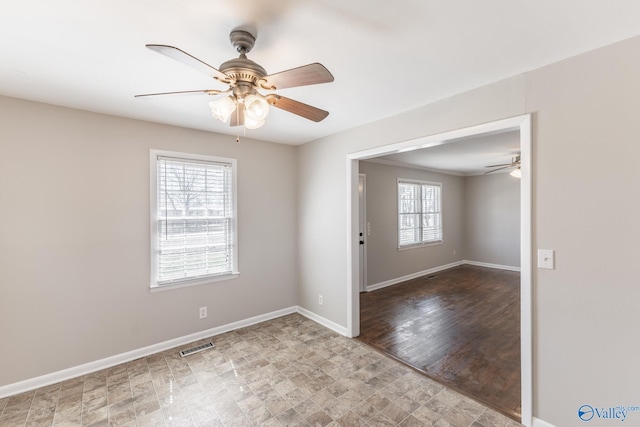 unfurnished room featuring plenty of natural light, a ceiling fan, and baseboards