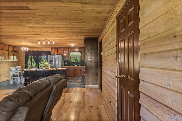 living room with an inviting chandelier, wood walls, wood-type flooring, and wooden ceiling