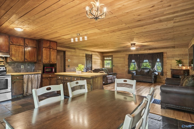 dining space featuring ceiling fan with notable chandelier, wooden walls, and wooden ceiling