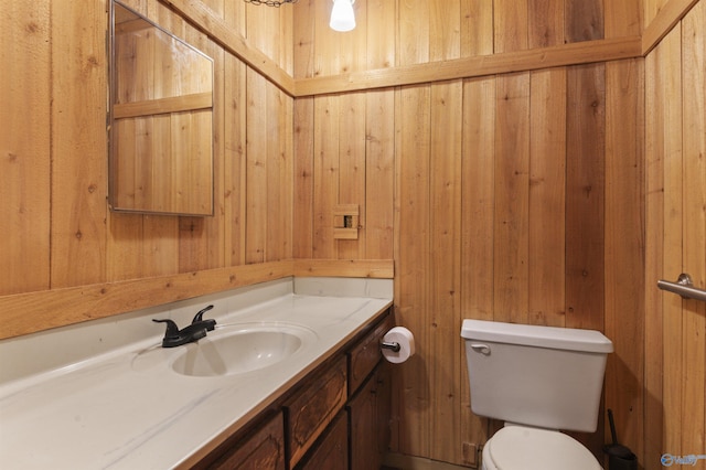 bathroom with vanity, wooden walls, and toilet