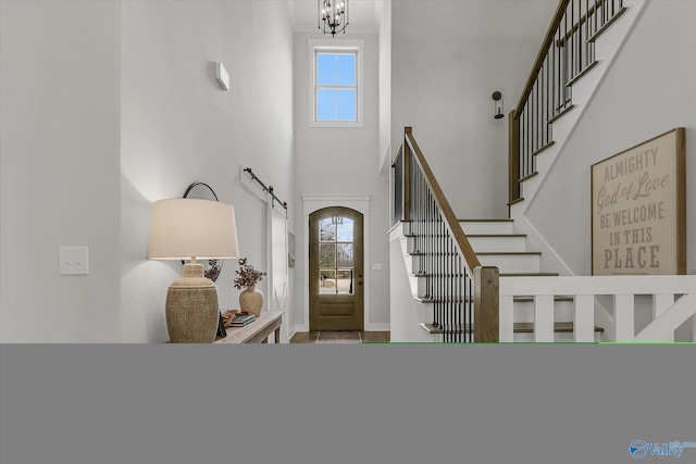 foyer entrance featuring a high ceiling, a wealth of natural light, and a notable chandelier