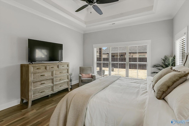 bedroom with ceiling fan, dark hardwood / wood-style floors, and a raised ceiling