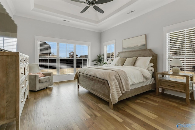 bedroom featuring hardwood / wood-style floors, ceiling fan, and a tray ceiling