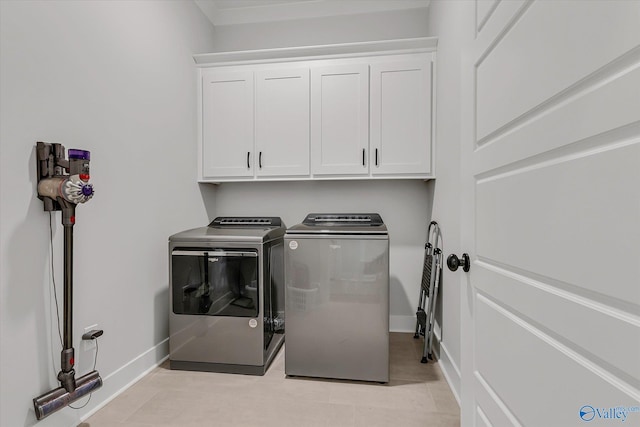 clothes washing area featuring cabinets, independent washer and dryer, and light tile patterned flooring