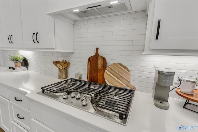 room details with tasteful backsplash, custom exhaust hood, stainless steel gas cooktop, and white cabinets