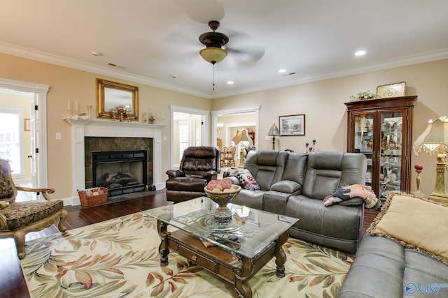 living room featuring dark wood-type flooring, a healthy amount of sunlight, ceiling fan, and a tile fireplace